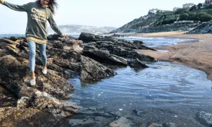Une jeune femme profite d'une randonnée bord de mer, naviguant sur des rochers près de l'eau.