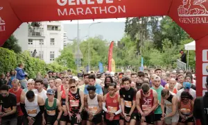 Des coureurs se préparent au départ de la course 10km Genève, sous une arche rouge "Genève + Marathon".