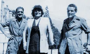Trois personnes posent devant un paysage. L'homme de gauche, peut-être le fondateur Millet, sourit.