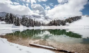 Lac d'altitude enneigé, reflétant les sapins et les montagnes. Idéal pour découvrir que faire autour de Villard de Lans en hiver.