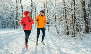 Un couple profite de l'air frais en courant sous la neige dans une forêt enneigée.