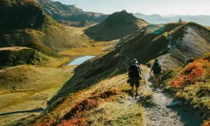 Deux randonneurs explorent un sentier de montagne pittoresque, profitant des couleurs d'automne et des paysages magnifiques. Les fiz sont en pleine aventure.