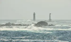 Deux phares se dressent sur des îlots rocheux battus par les vagues, au large de l'île d'Ouessant.