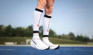 Manchons de compression mollet : pour une meilleure récupération et performance. Ces manchons blancs avec logo Compressport sont portés par un coureur.