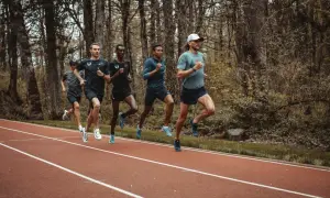 Cinq coureurs s'entraînent sur une piste, leurs foulées rythmées par un entraînement de fractionné course intense.