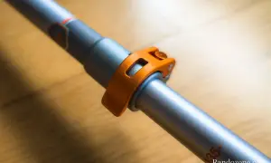 Gros plan sur le mécanisme de serrage orange d'un bâton de marche pliable ou télescopique, prêt pour l'aventure.