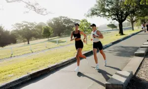 Deux femmes profitent d'un entraînement de course à pied matinal dans un parc verdoyant, leurs sourires reflétant leur plaisir.