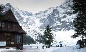 Maison en bois au pied des montagnes enneigées des Tatras en Pologne. Un lac gelé s'étend devant.