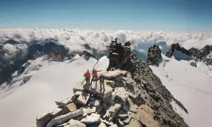 Des alpinistes atteignent le sommet rocheux, dominant un océan de nuages. Un panorama à couper le souffle, un véritable grand paradis.