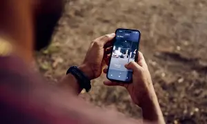 Une application de fitness running s'affiche sur un smartphone tenu par une personne.