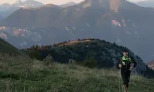 Un coureur en plein effort, bâtons en main, sur un sentier de montagne. Un aperçu de son plan d'entraînement UTMB.