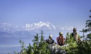 Trois randonneurs contemplent les sommets enneigés après une randonnée dans le Jura.
