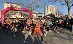 Départ d'une course à Bourg-en-Bresse sous un ciel bleu. Des coureurs s'élancent sous une arche rose.