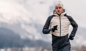 Un homme court par temps froid, portant une veste pour courir l'hiver, un bonnet et des gants.