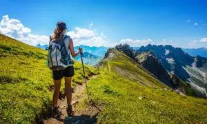 Une randonneuse admire le panorama spectaculaire des Alpes françaises. Le sentier serpente à travers des prairies verdoyantes, offrant une vue imprenable sur les montagnes majestueuses.