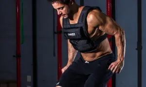 Un homme s'entraîne en courant avec un gilet lesté, intensifiant son effort dans une salle de sport.