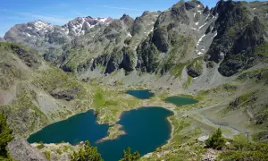 Vue panoramique sur le lac Robert et ses jumeaux, entourés de montagnes escarpées aux sommets enneigés. Un paysage alpin spectaculaire.