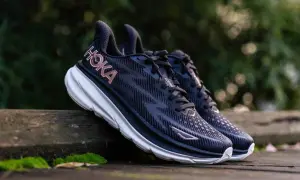 Paire de chaussures de course Hoka Clifton 9, bleues foncées avec logo rose, posées sur un banc en bois. Avis sur le confort et la performance.