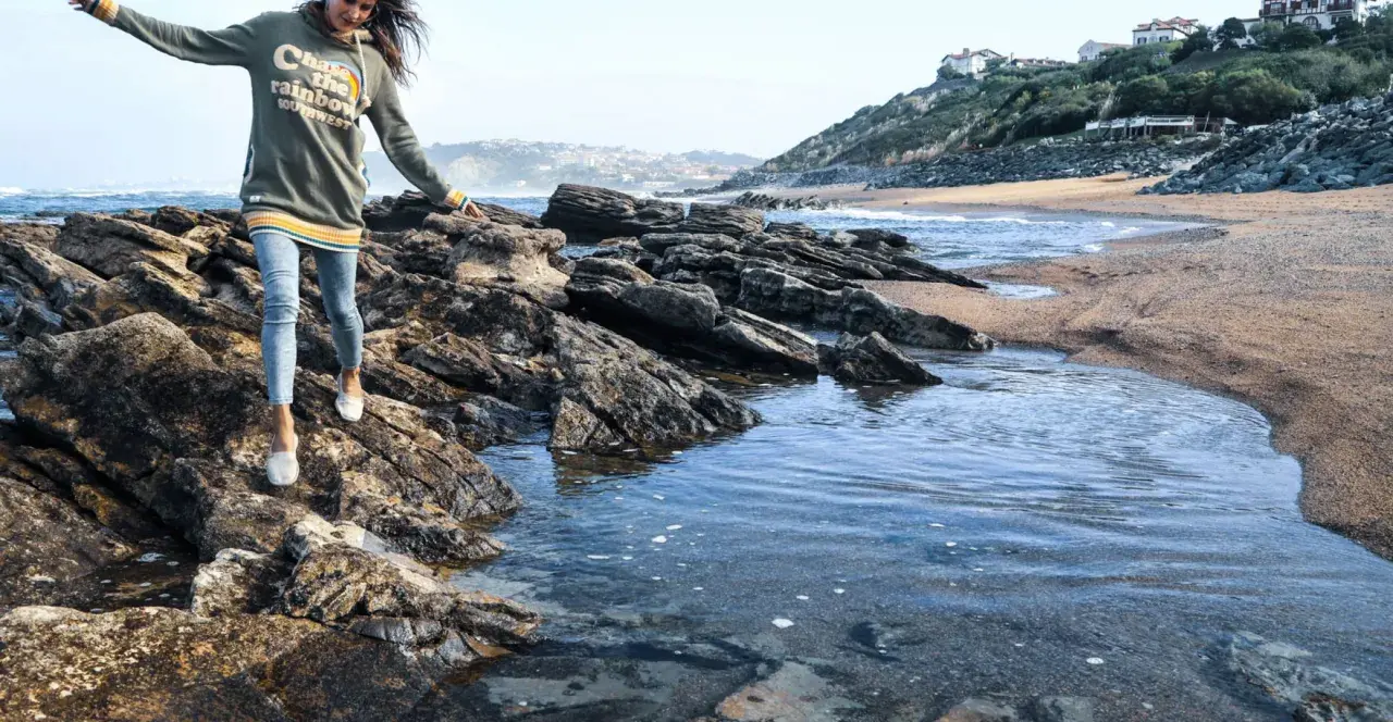 Une jeune femme profite d'une randonnée bord de mer, naviguant sur des rochers près de l'eau.