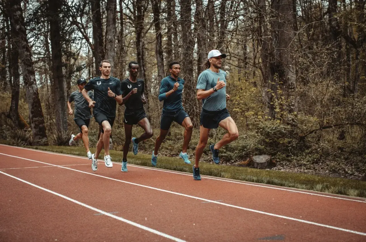 Cinq coureurs s'entraînent sur une piste, leurs foulées rythmées par un entraînement de fractionné course intense.