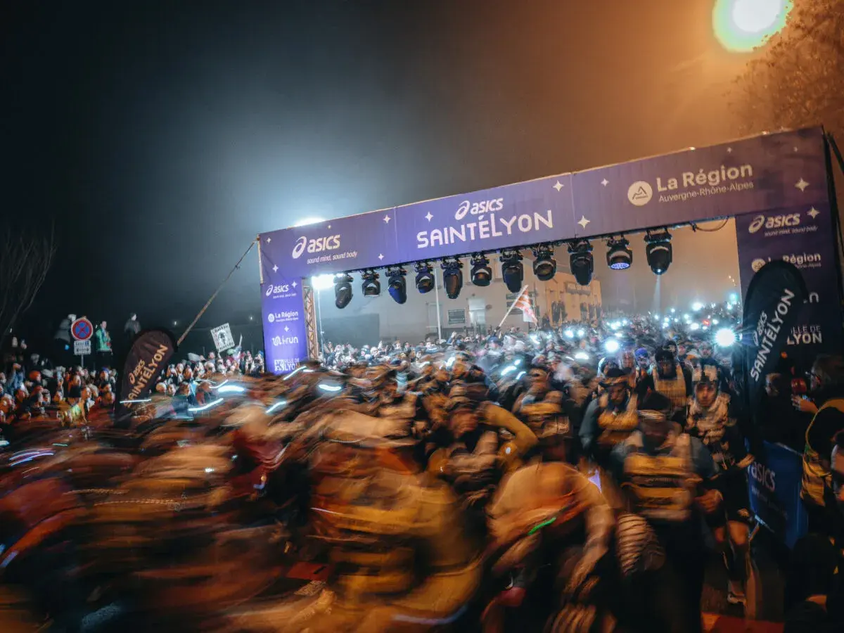 Foule de coureurs au départ de la SaintéLyon, sous un portique illuminé. Les résultats de cette course nocturne promettent d'être intenses.