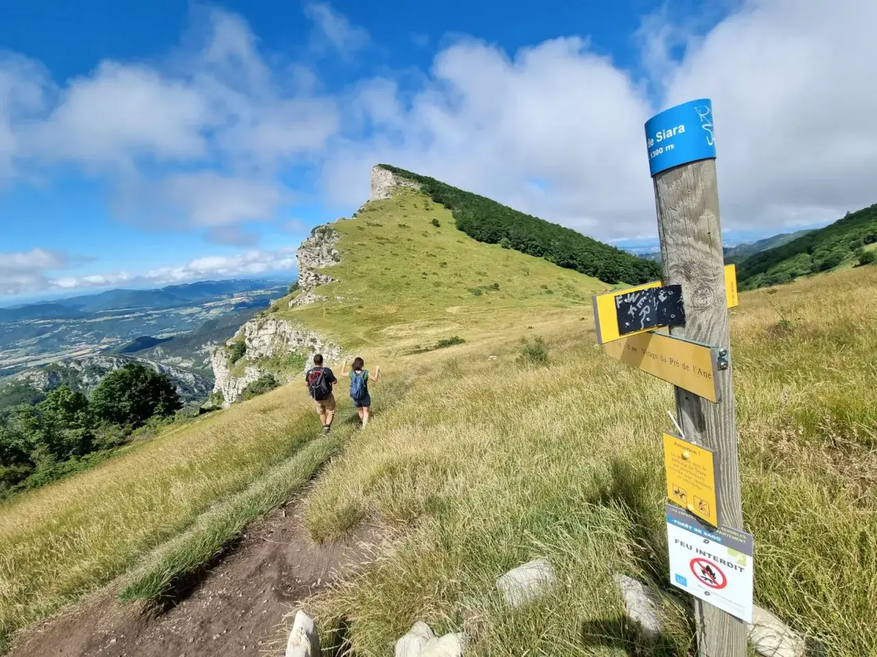 Deux randonneurs sur un sentier menant aux 3 Becs, avec un panneau indiquant
