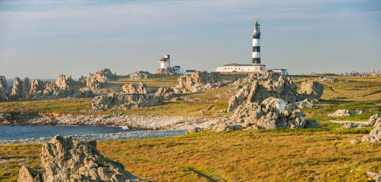 Phare noir et blanc et phare rouge sur l'île d'Ouessant, entourés de rochers et de landes.