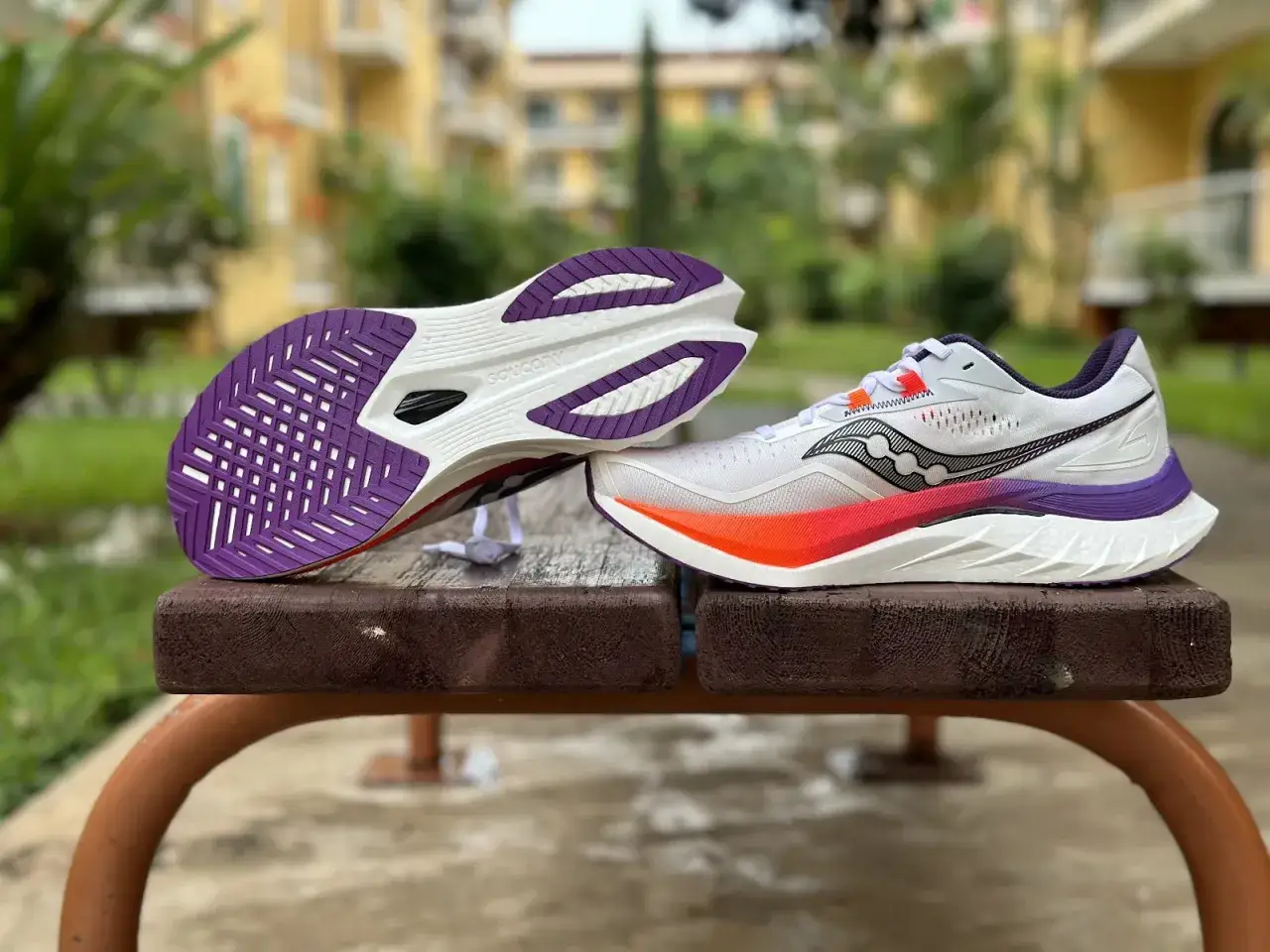 Chaussures de course Saucony Endorphin Speed 4, pr&ecirc;tes pour un test. Semelle ext&eacute;rieure violette et semelle interm&eacute;diaire blanche avec d&eacute;grad&eacute; orange et rose.
