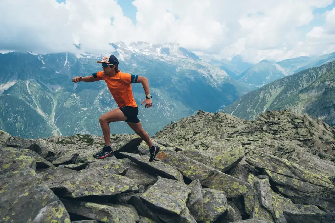 Patrick Bohard court sur un sentier rocheux, dominant un paysage montagneux spectaculaire.