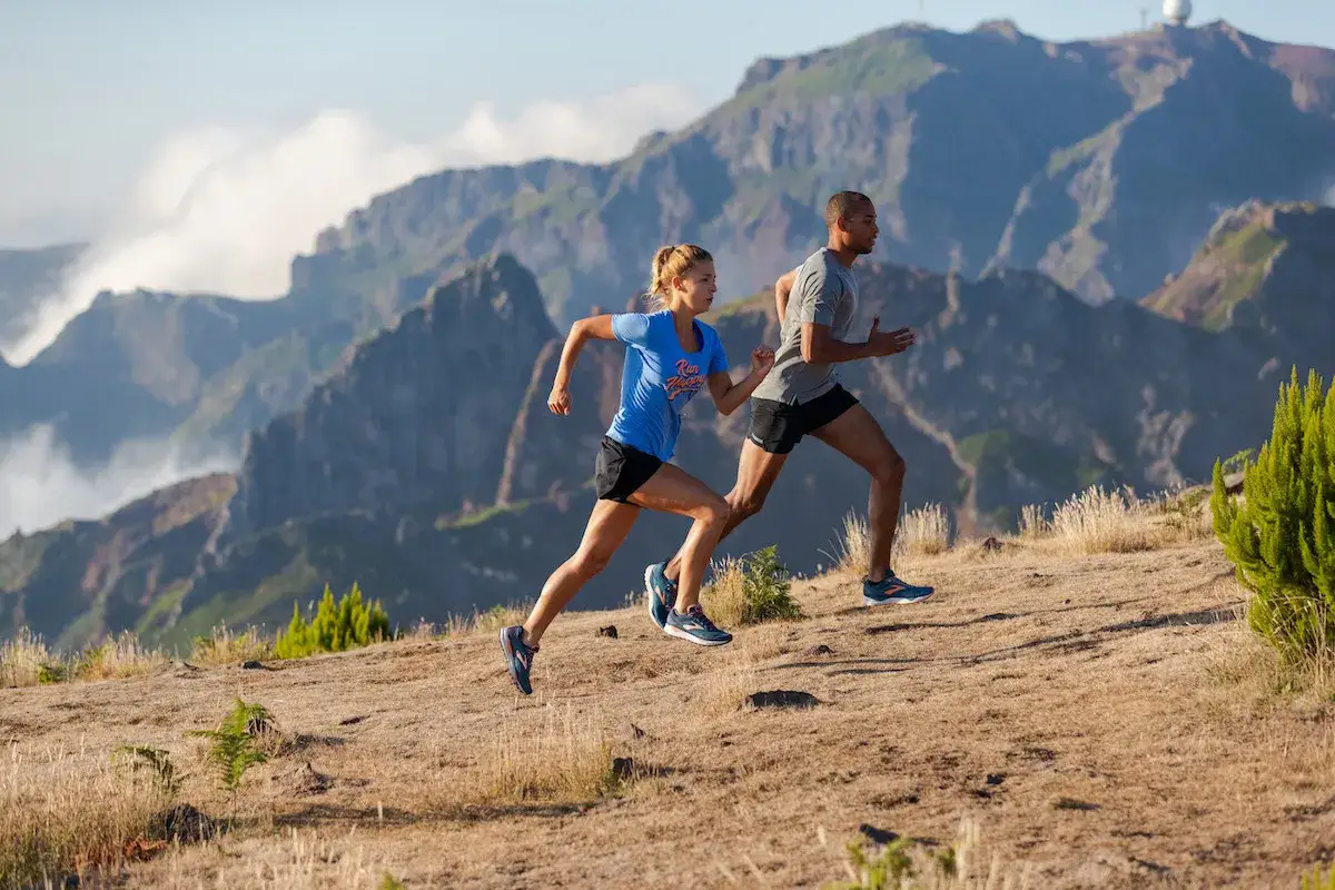 Un couple court dans un paysage montagneux, profitant de leur s&eacute;ance de sport pour courir 20 minutes par jour.