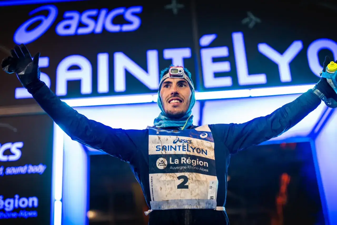 Un coureur c&eacute;l&egrave;bre les r&eacute;sultats de la Saint&eacute;lyon, bras lev&eacute;s, portant le dossard num&eacute;ro 2.