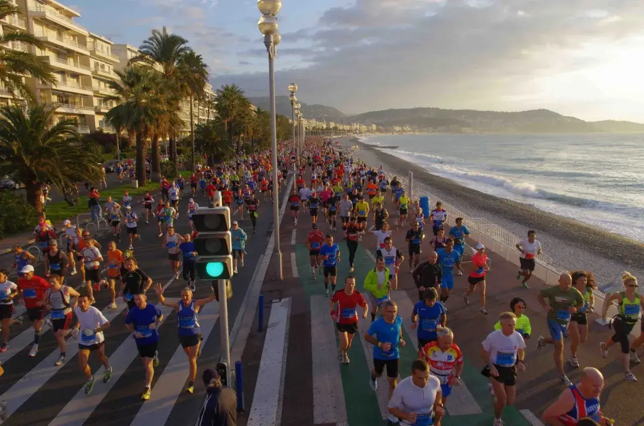 Une foule court sur la promenade des Anglais &agrave; Nice, le soleil se levant sur la mer.