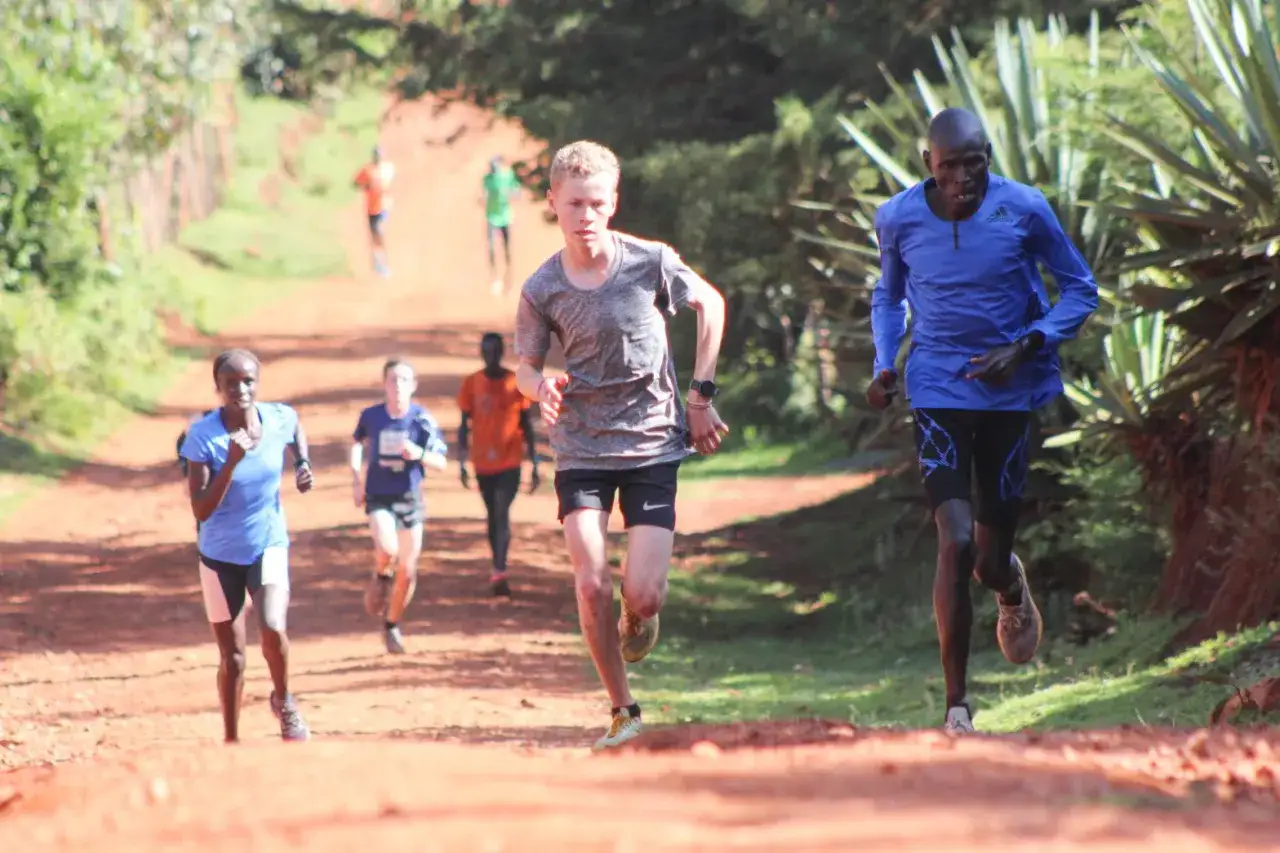 Des coureurs s'entra&icirc;nent sur un chemin de terre, certains en bleu, d'autres en gris ou orange. Un entra&icirc;nement de fractionn&eacute; course intense.