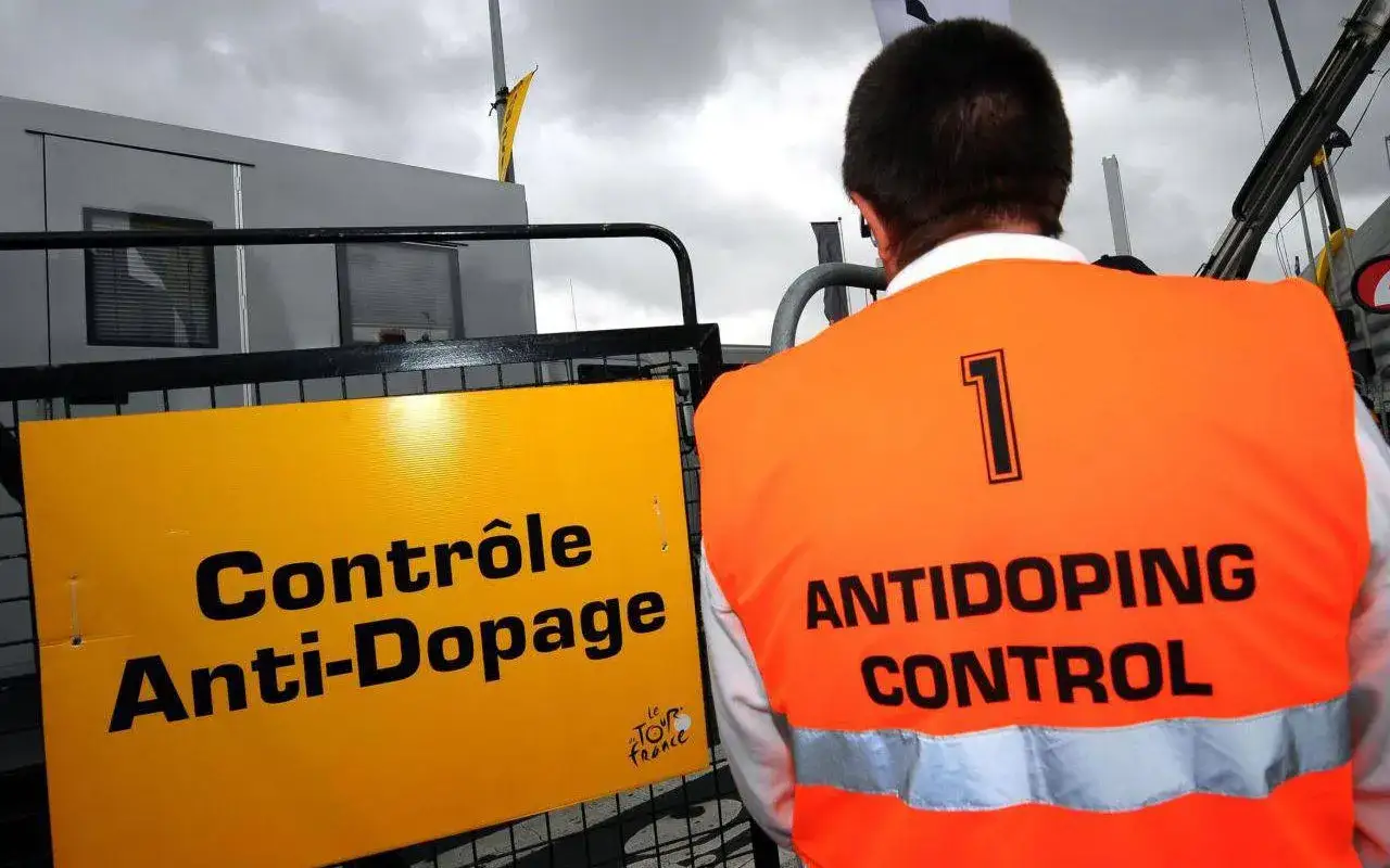 Contr&ocirc;le anti-dopage sur le Tour de France. Un agent porte un gilet orange 
