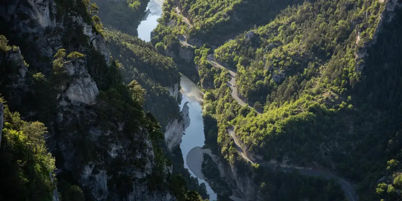 Vue aérienne des Gorges du Tarn, une route sinueuse longeant la rivière. Idéal pour visiter les gorges du Tarn en 3 jours.