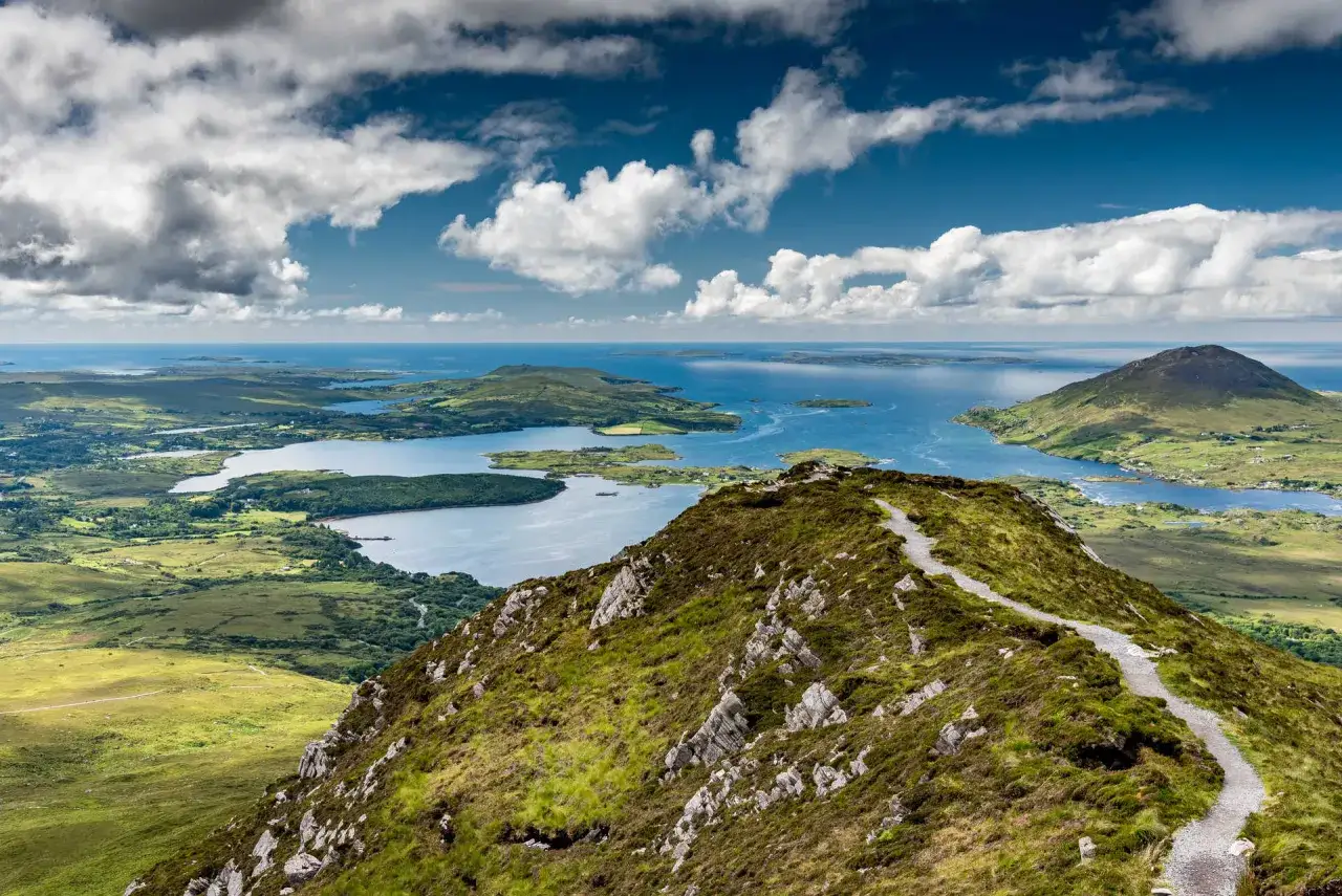 Sentier de randonn&eacute;e Connemara, vue panoramique sur les lacs bleus et les &icirc;les verdoyantes sous un ciel nuageux.