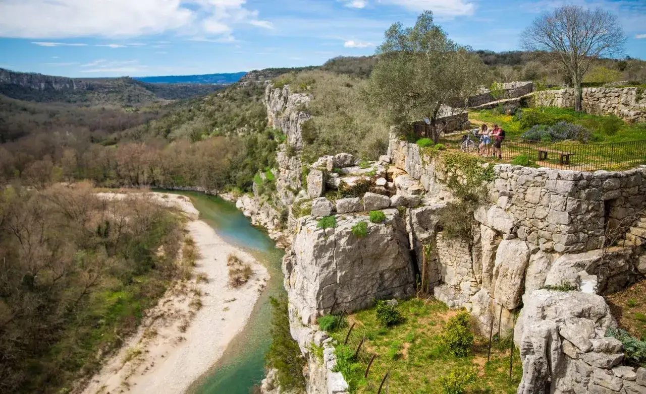 Vue panoramique sur le trail gorge de l'Ard&egrave;che. Deux cyclistes admirent le paysage depuis un belv&eacute;d&egrave;re en pierre.