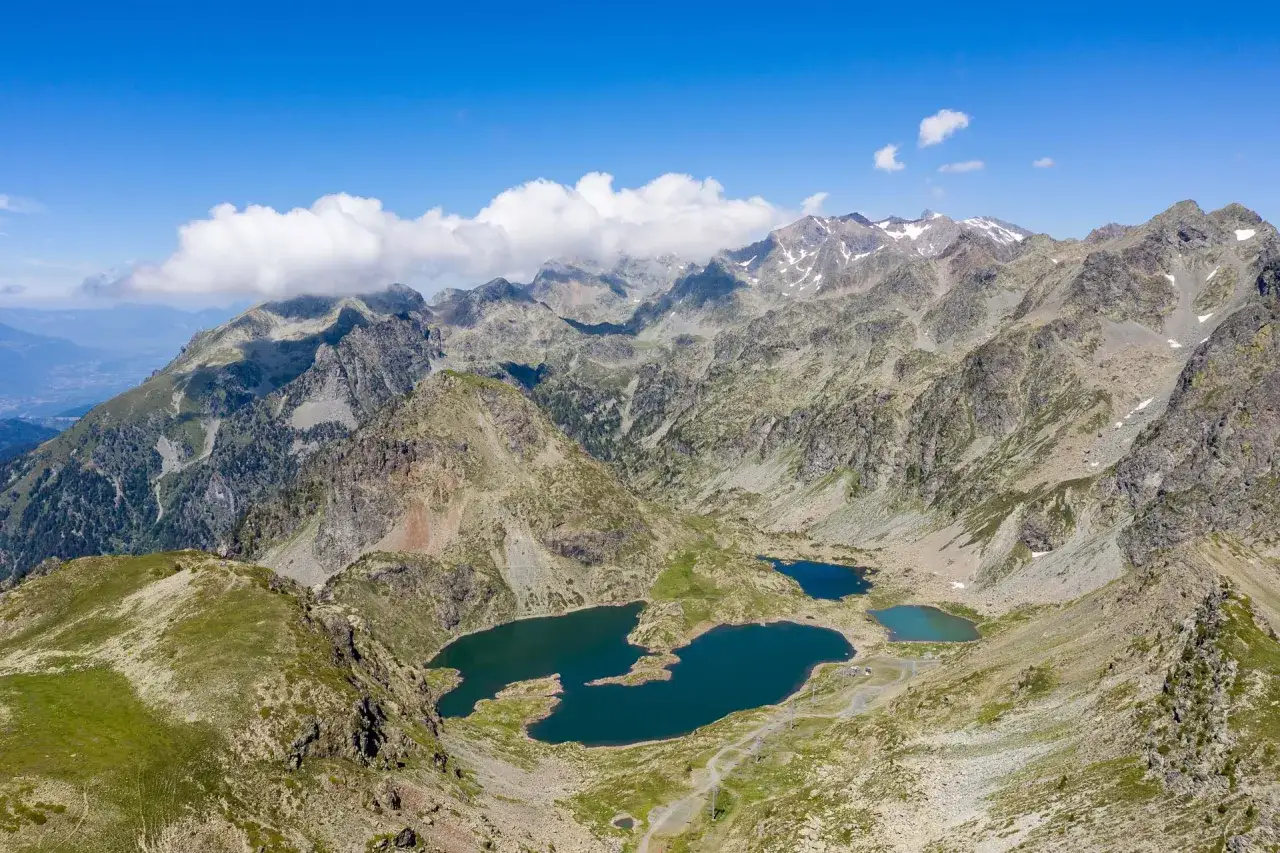 Vue aérienne des lacs Robert, joyaux bleus nichés au cœur de montagnes rocailleuses et verdoyantes sous un ciel d'été.