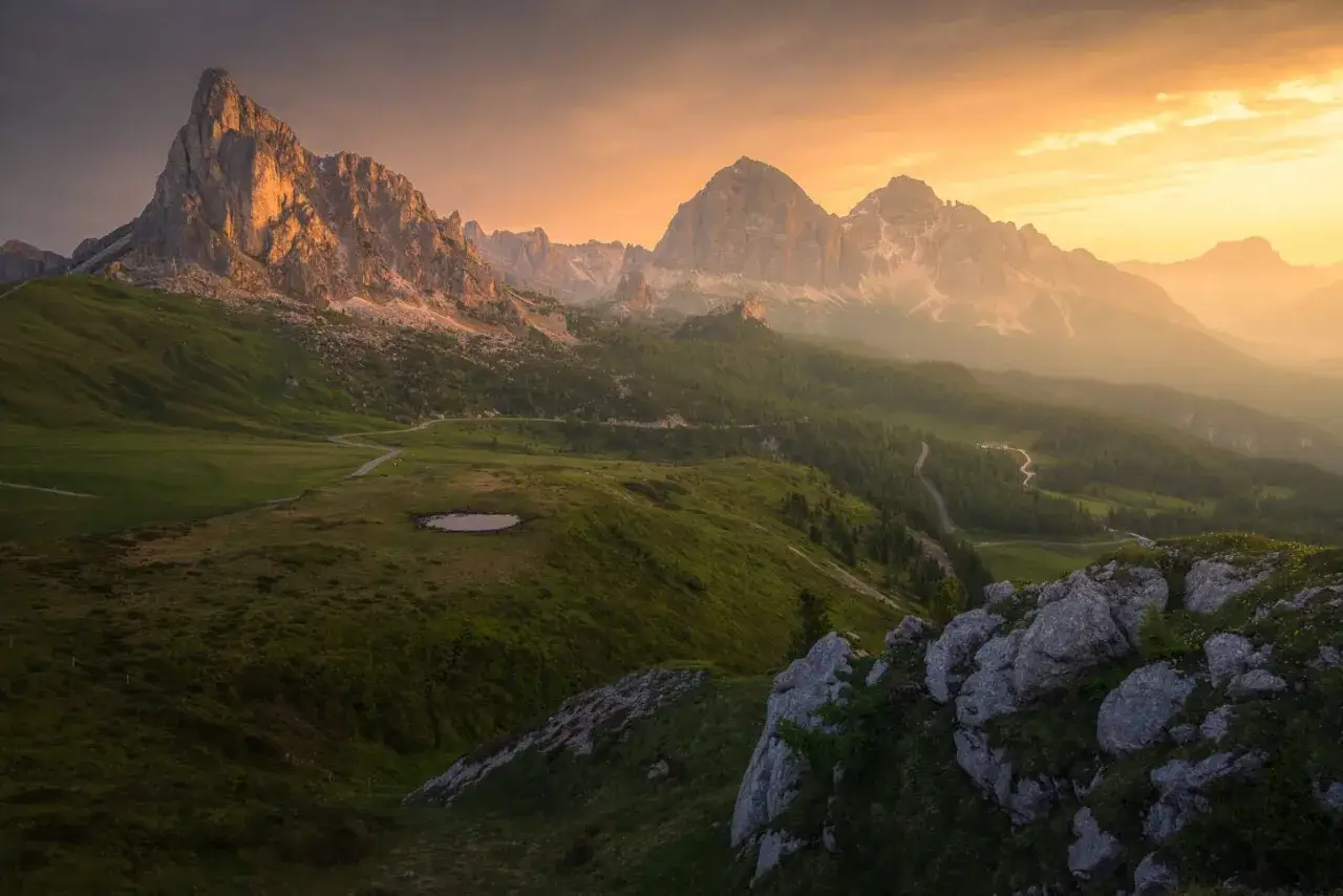 Magnifique paysage des Dolomites au coucher du soleil, idéal pour un trek. Des montagnes imposantes, des prairies verdoyantes et une route sinueuse invitent à l'aventure.