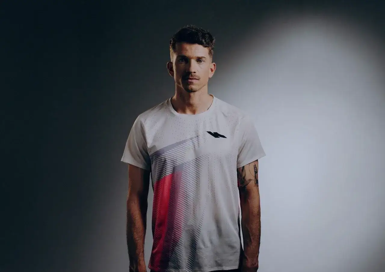 Mathieu Blanchard, athlète concentré, porte un t-shirt blanc avec un motif graphique audacieux.