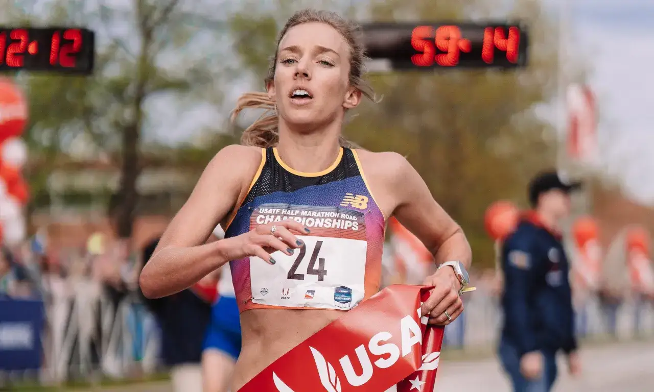 Athl&egrave;te en pleine course, dossard 24, franchissant la ligne d'arriv&eacute;e d'un semi-marathon. Le chronom&egrave;tre affiche 59:14.