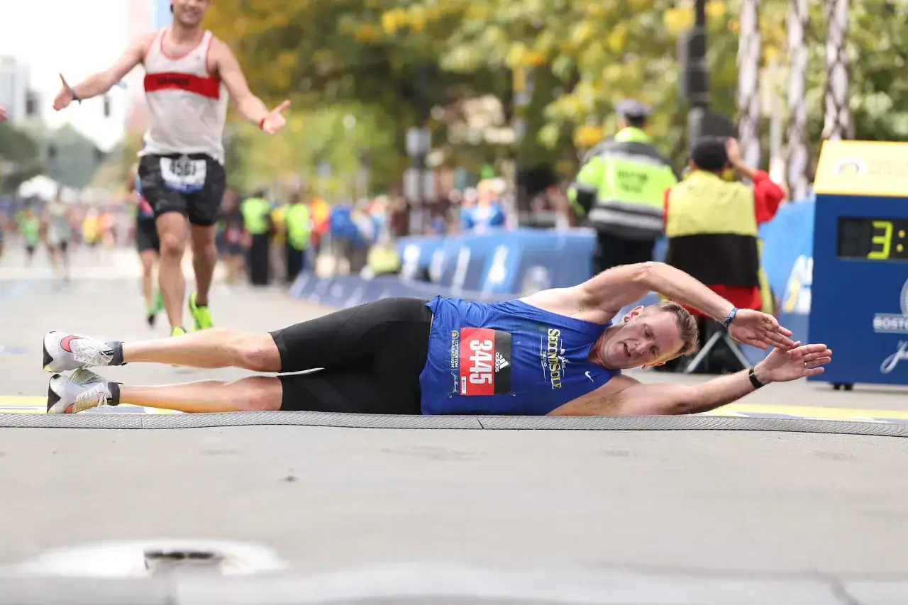 Un coureur s'effondre sur la ligne d'arriv&eacute;e, son allure marathon 3h t&eacute;moignant de son effort intense.