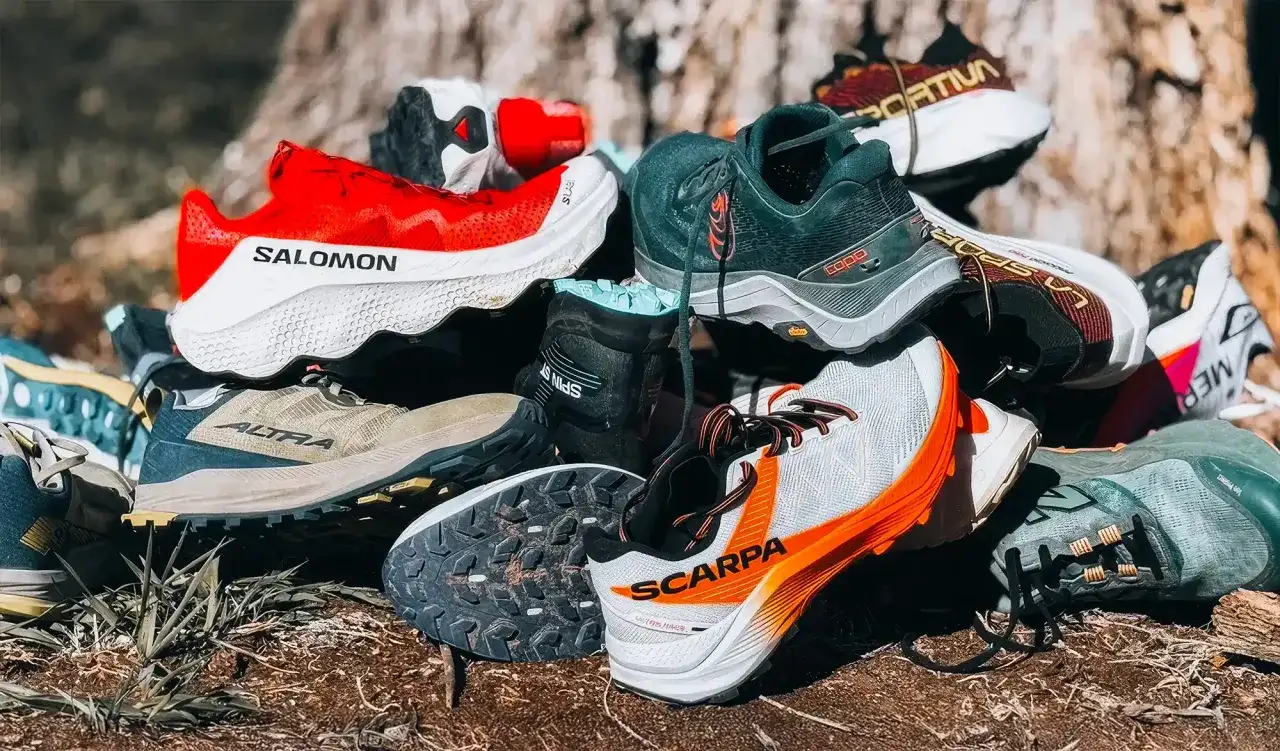 Pile de chaussures de trail et de running, montrant la diff&eacute;rence de crampons et de maintien pour affronter tous les terrains.