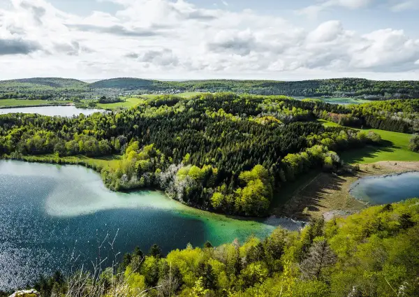 Paysage jurassien avec lacs et forêts verdoyantes, idéal pour une randonnée Jura 5 jours.